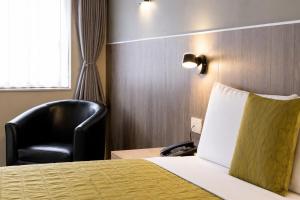 a hotel room with a bed and a black chair at Airport Manor Inn in Auckland