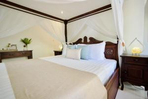 a bedroom with a canopy bed with white sheets at Poinciana Resort in Tejakula +181 photos