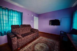 a living room with a couch and a flat screen tv at Shabeer's White Castle in Ooty