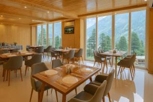 a restaurant with tables and chairs and large windows at Hotel The Fortune Luxury Rooms Near Mall Road Manali By Vistas - Best Selling Centrally Heated Property 2025-26 in Manāli