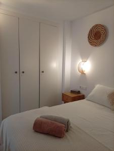 a bedroom with a white bed with a brown towel on it at Appartement piscine Rosas in Roses +39 photos