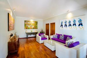 a living room with purple and white furniture and a piano at Poinciana Resort in Tejakula