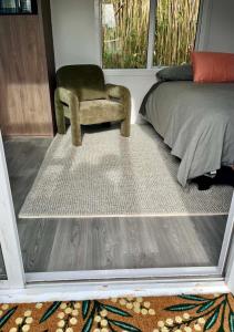 a bedroom with a chair and a bed and a rug at Oasis in onerahi in Whangarei +4 photos