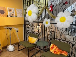 a room with two chairs and a table and flowers at Laloon Guesthouse in Hat Yai