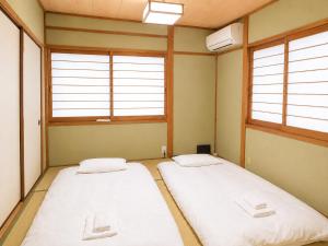 two beds in a room with two windows at 響-Garden House- in Toyonaka