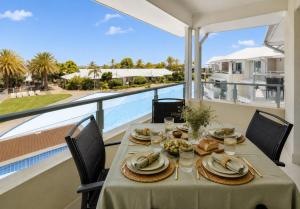 a dining room with a table and a view of a pool at Luxury Renovated Resort Studio Apartment - Oaks Pacific Blue in Salamander Bay