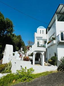 a white building with a balcony and a blue sky at 藍屋頂民宿Blue Dome in Puli