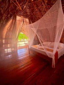 a bed in a room with a net at Dos Playa EcoCamp Daracoton Island in El Nido