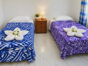 two beds with white flowers on them in a room at Mouare Hideaway in Arutanga