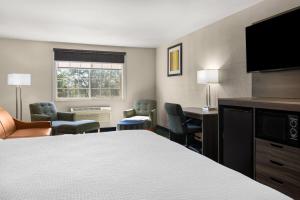 a hotel room with a bed and a desk and chairs at Baymont by Wyndham Santa Fe in Santa Fe
