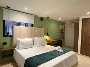 a bedroom with a large white bed with green walls at Arcadia Hotel in Cartagena de Indias +63 photos