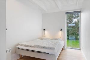 a white bedroom with a bed and a window at 8574-Grenaa-Annavej-13 in Gjerrild