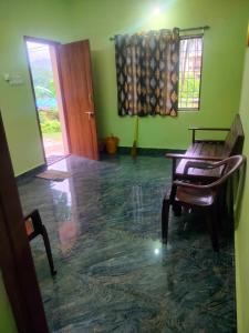 a room with a chair and a table and a door at Manjunatha nilaya sute delux ordinary room in Kollūru