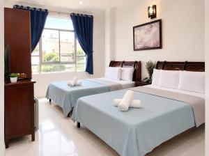 a bedroom with two beds and a tv and a window at SG Cozy2 Hotel - Pham Ngu Lao Street in Ho Chi Minh City