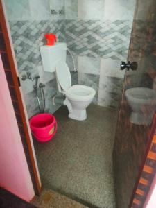 a bathroom with a toilet and a red bucket at Manjunatha nilaya sute delux ordinary room in Kollūru