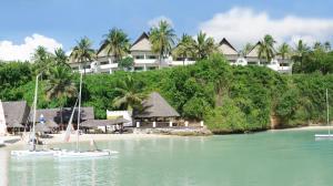 a resort on a beach with boats in the water at Mnarani Beach Club in Kilifi