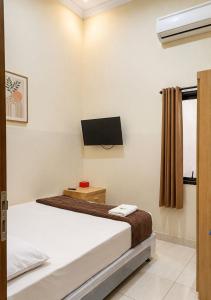 a bedroom with a bed and a tv on the wall at Solota Boutique Hotel Syariah in Bonorejo
