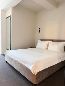 ein Schlafzimmer mit einem großen Bett mit weißer Bettwäsche in der Unterkunft Hotel Keto in Podgorica