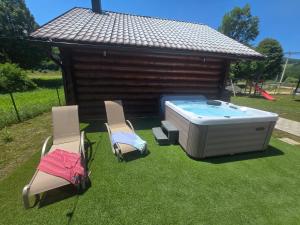 two chairs and a hot tub in a yard at Kuća za odmor Brlog in Otočac