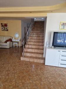 a living room with a staircase with a couch and a television at apartament maia 2 in Turda