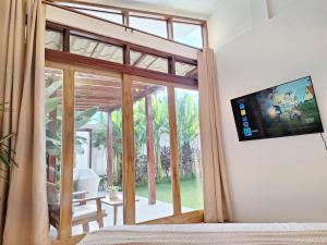 a bedroom with a large window with a tv on the wall at Three-Bedroom Luxury Garden Villa by Sing Siargao in General Luna