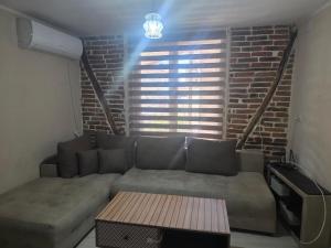 a living room with a couch and a brick wall at Къща Теяна in Tryavna