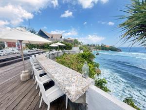 a table with chairs and an umbrella and the ocean at The Palms Ceningan Hotel in Nusa Lembongan