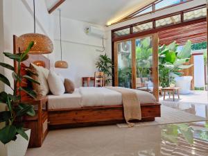 a bedroom with a wooden bed and a patio at Three-Bedroom Luxury Garden Villa by Sing Siargao in General Luna
