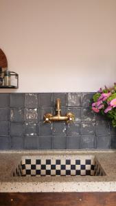 a kitchen sink with a brass faucet on a wall at Bed en kerk monumentale 2 slaapkamer woning in Hoorn
