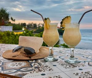 a table with two glasses and a hat and sunglasses at The Palms Ceningan Hotel in Nusa Lembongan