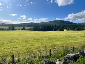 a field of green grass with mountains in the background at The Studio at Torr Leathann - Modern Studio in Stittenham +2 photos