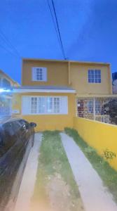 a car parked in front of a yellow house at Villa lux in Portmore