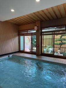 a swimming pool in a house with a large window at Towa Onsen and Ryokan in Ban Nong Tangme