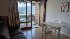 a living room with a table and a view of a balcony at Résidence Serre-Ponçon in Chorges