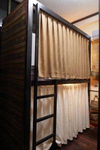 a ladder standing in front of a window with curtains at Non Pakse Hostel in Pakse
