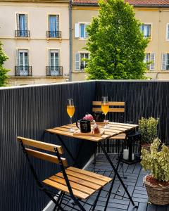 a table and chairs on a balcony with wine glasses at Appart&Spa Devosge in Dijon
