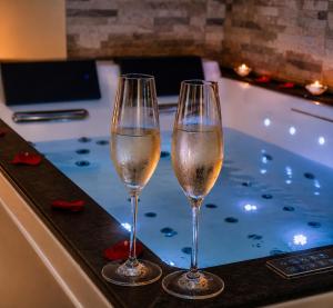 two glasses of wine sitting on a bar next to a tub at Appart&Spa Devosge in Dijon
