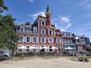 a large red building with a clock tower on a beach at La parenthèse de la Bouvaque in Abbeville