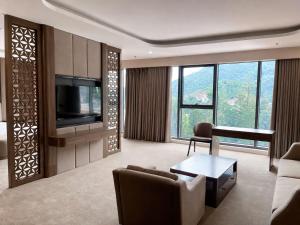 a living room with a television and a couch and a table at Muong Thanh Luxury Moc Chau Hotel in Mộc Châu