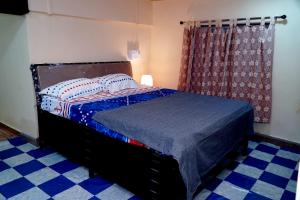 a bedroom with a bed with a blue comforter at Sitara Homestay in Ratnagiri
