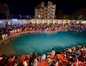 a crowd of people sitting around a pool at night at جمصه Amoun Chalet Gamasa in Jamaşah +18 photos