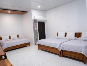 two beds in a room with white walls at Tanjung Inn in Wonosari