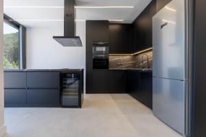 a kitchen with black cabinets and a stainless steel refrigerator at BlackPine Villa in Amisianá