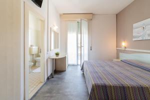 a hotel room with a bed and a bathroom at Hotel Carol in Cesenatico