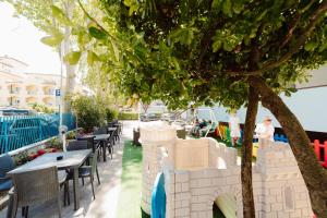 a patio with tables and chairs and a tree at Hotel Carol in Cesenatico