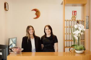 two women standing next to a wooden table at Hotel Carol in Cesenatico