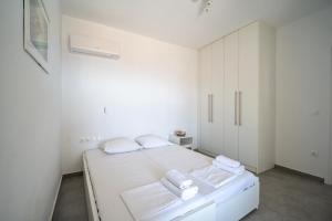 a white bedroom with a bed with towels on it at Psaraki House Serifos in Serifos Chora