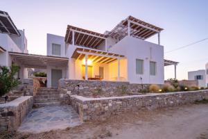 a white house with a stone wall and stairs at Psaraki House Serifos in Serifos Chora