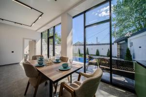 a dining room with a table and chairs and large windows at Qafqaz Four Seasons in Gabala