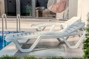 two white lounge chairs next to a swimming pool at Qafqaz Four Seasons in Gabala